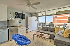 Un apartamento moderno con kitchenette, un sofá, una mesa de centro y un balcón con vista a la playa.