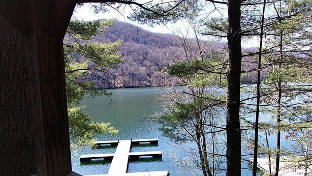 A view of a lake with dock platforms, surrounded by trees and hills.