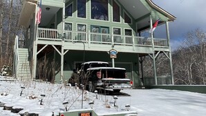 A large, two-story building with a green roof and a balcony. A black pickup truck is parked in front.