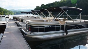A row of stationary boats docked at a pier with a wooden walkway.