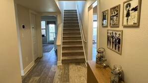 A hallway with a wooden floor, a staircase, and a wooden cabinet with jars. - Beach Nut Bungalow:  Two bedroom home in Pamlico Point (Ocracoke)