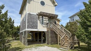 A two-story building with a wooden staircase leading to a balcony. - Beach Nut Bungalow:  Two bedroom home in Pamlico Point (Ocracoke)
