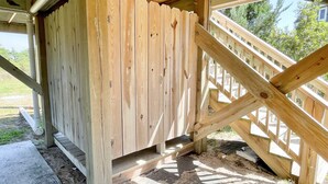 A wooden staircase leading up to a covered area with a view of the outdoors. - Beach Nut Bungalow:  Two bedroom home in Pamlico Point (Ocracoke)