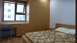 Ein Schlafzimmer mit Bett, Schreibtisch, Stuhl und Kleiderschrank.