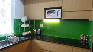 Eine Küche mit Holzausstattung, einer Mikrowelle, einer grünen Spritzschutzwand und verschiedenen Küchenutensilien auf der Arbeitsfläche.