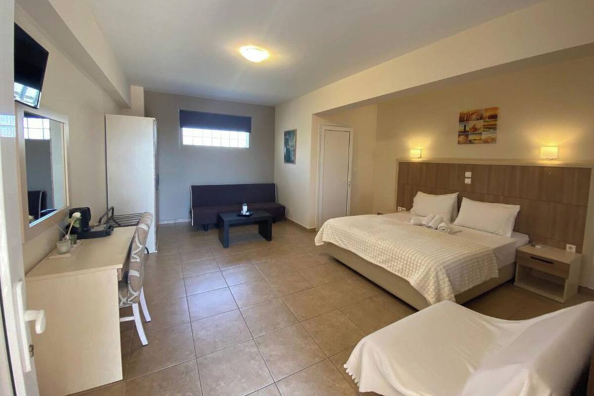 Una habitación de hotel con cama, escritorio, silla, sofá y una mesita.