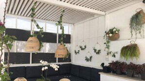 Un intérieur moderne aux couleurs contrastées, en noir et blanc, comprenant une table en bois, un canapé noir et diverses plantes suspendues.