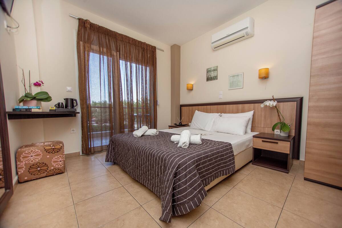 Habitación de hotel con cama, mesita de noche y un pequeño espacio para sentarse.