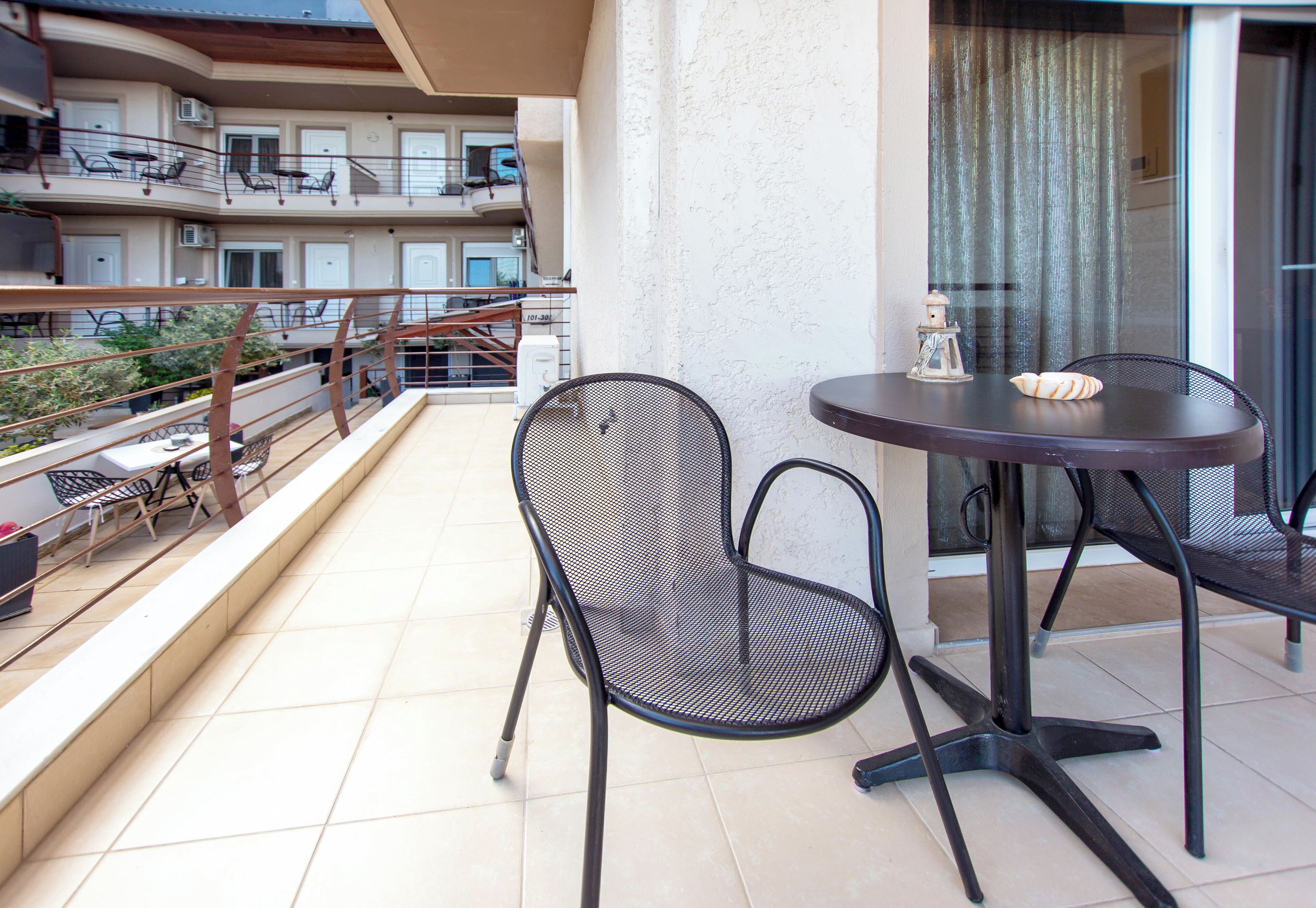 A balcony with a round table and two chairs, overlooking a residential area with multiple balconies.