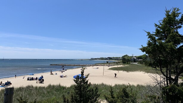 A beach with people, umbrellas, and a volleyball net.
