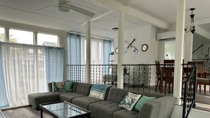 A spacious living room with a sectional sofa, a glass coffee table, and a dining area with chairs.