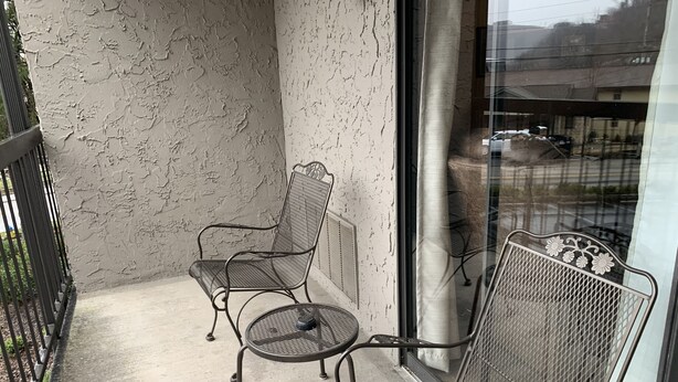 Un balcone con due sedie in metallo e un tavolino rotondo.