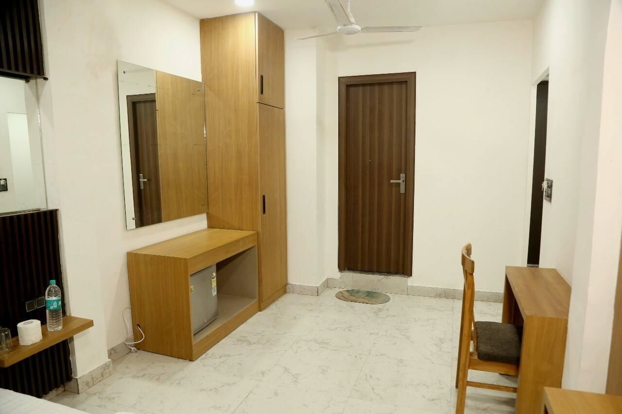Una habitación con un armario de madera, una silla, una mesita y un espejo en la pared.