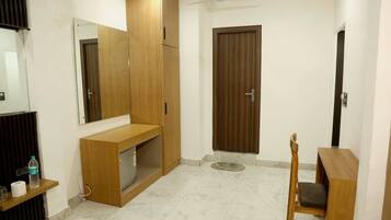 A room with a wooden cabinet, a chair, a small table, a door, and a mirror on the wall.