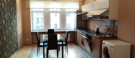 Een koelkast, een oven, een vaatwasser, kookgerei, borden en bestek