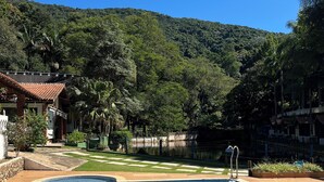 A swimming pool with tiled edges, surrounded by a wooden deck and a grassy area. - Beautiful site in Mairiporã - SP Wi - Fi (mairiporã)