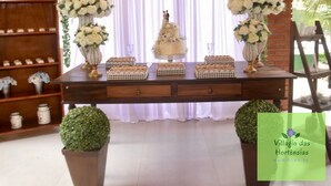 A decorated table with floral arrangements, a cake, and checkered boxes, set against a backdrop with white curtains and greenery. - Beautiful site in Mairiporã - SP Wi - Fi (mairiporã)