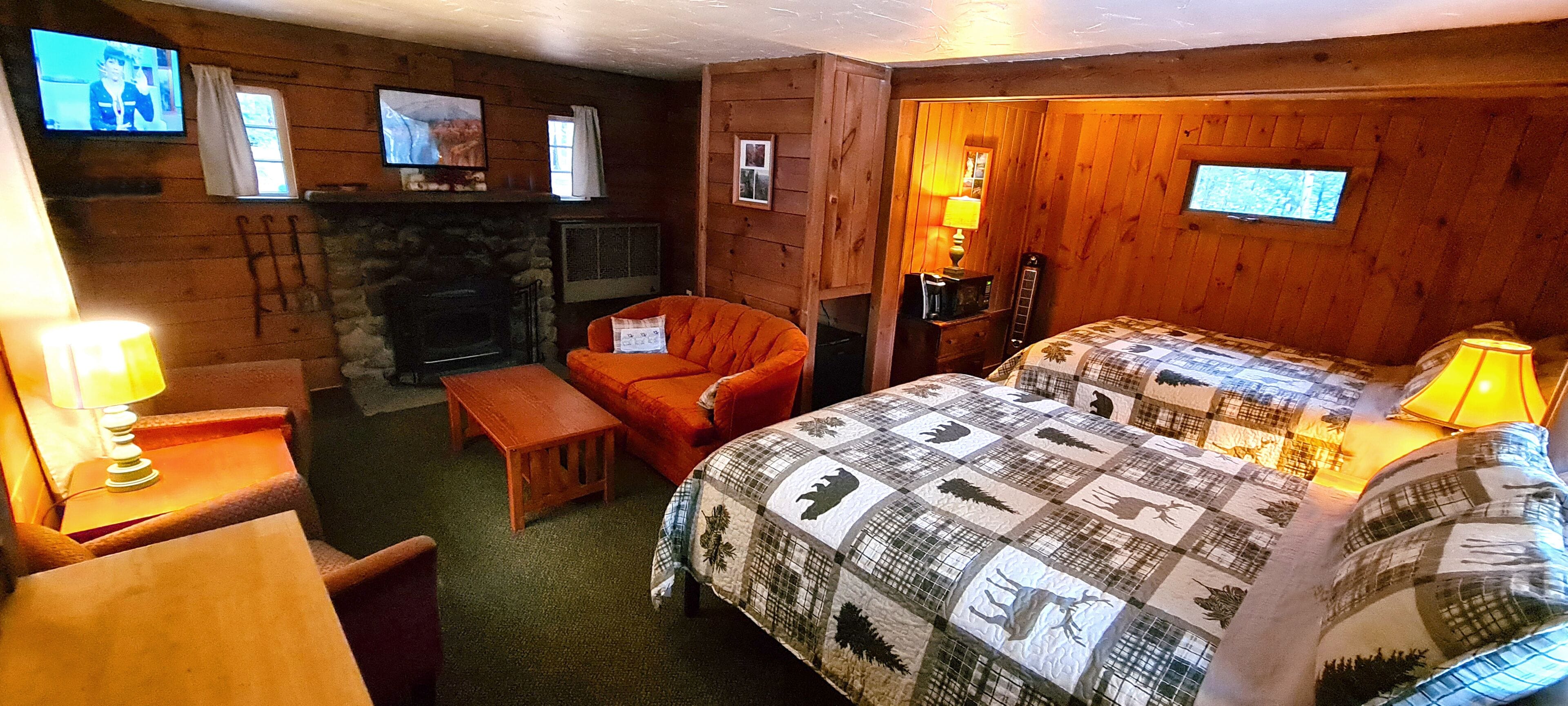 Una habitación acogedora con chimenea, una cama con colcha, un banco de madera y un televisor en la pared.
