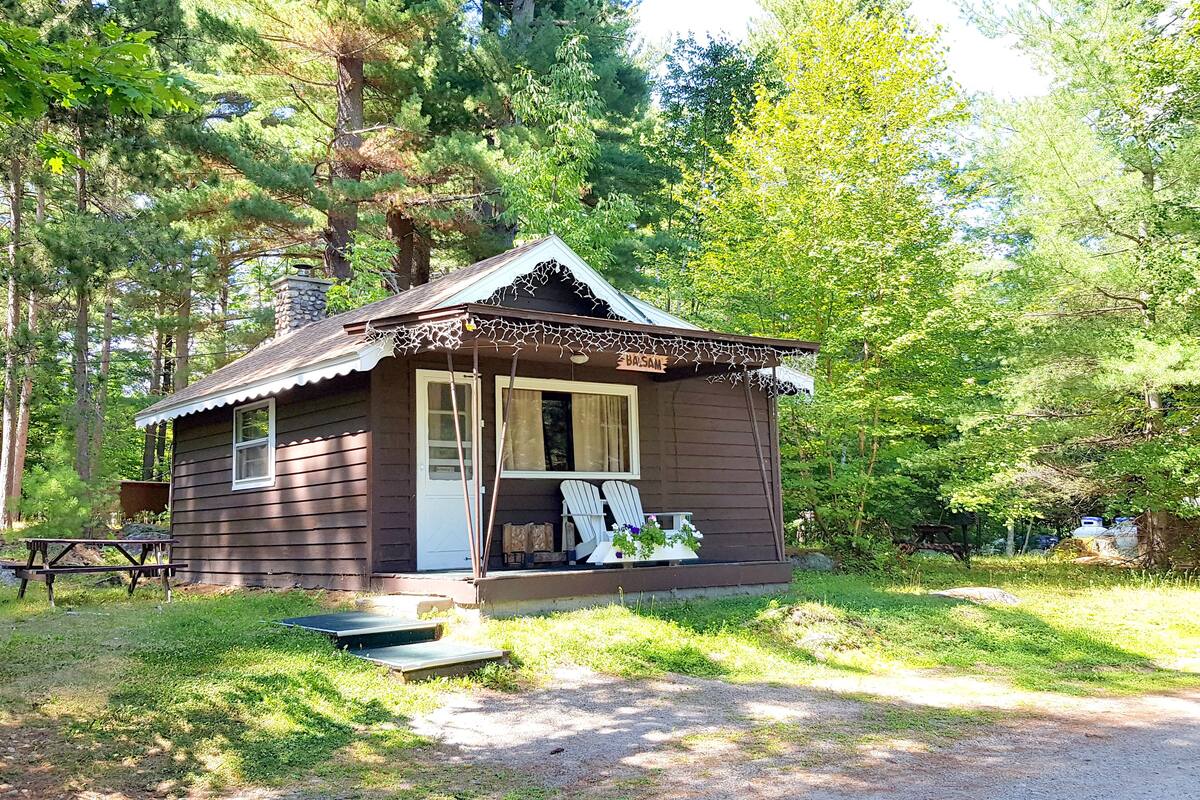 A small cabin with a porch, a bench, and a table.
