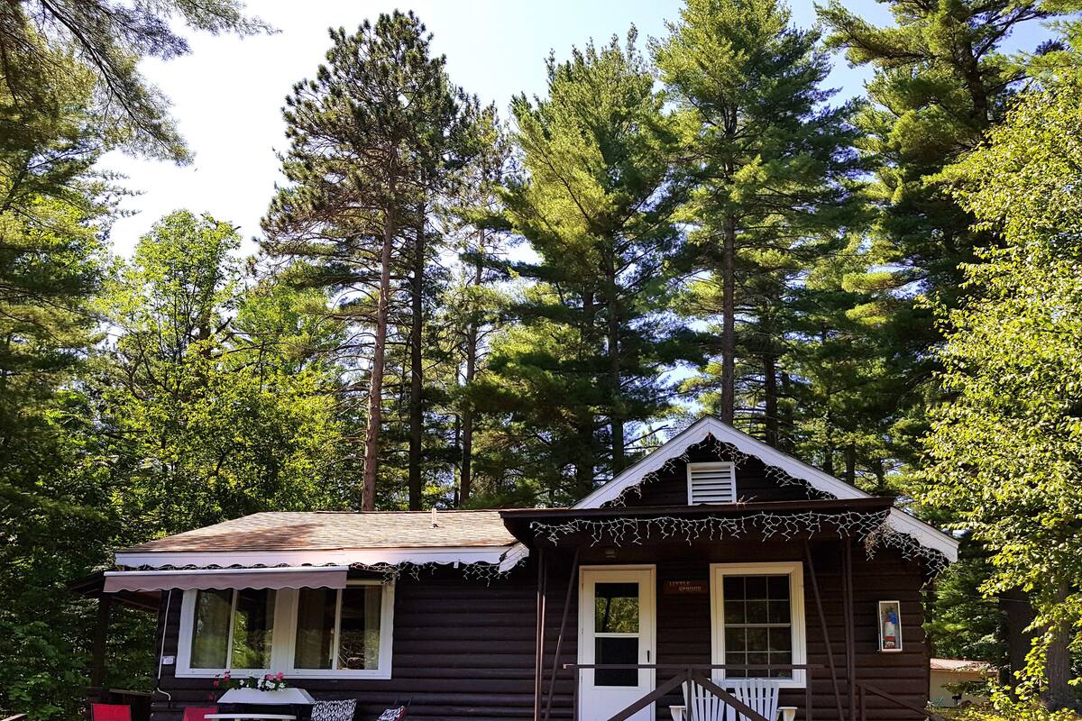 A rustic cabin with a porch, a small table, and two chairs.