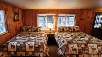 Una habitación tipo cabaña con dos camas, paredes de madera y ventanas amplias.