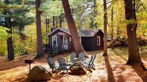 A cabin with a porch and outdoor seating area surrounded by tall trees. - The Wilderness Inn (Wilmington)