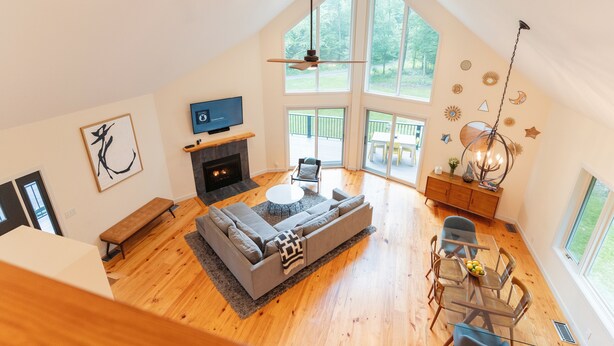 A spacious living area with a large gray sectional sofa, a fireplace, and a dining table with chairs.