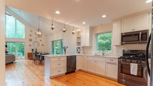 A modern kitchen with white cabinets, stainless steel appliances, and wooden flooring.