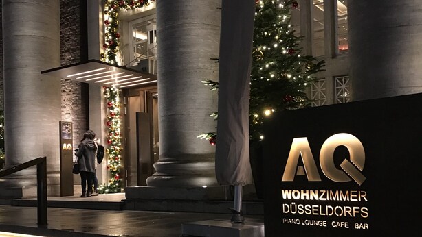 Une grande entrée avec un escalier menant à un bâtiment, décoré de guirlandes lumineuses de Noël et d’un sapin de Noël.