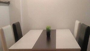 Ein rechteckiger Esstisch mit schwarzer Mittelseile, umgeben von vier Stühlen, zwei schwarz und zwei weiß. Auf dem Tisch steht ein kleiner Topfpflanze.