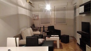 Ein modernes Wohnzimmer mit einer Couch, einem Couchtisch, einer TV-Kommode und einem Fenster.