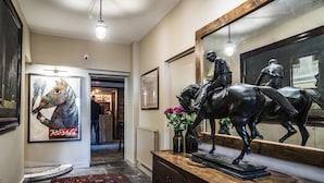 Een hal met een houten dressoir, een paardenbeeld, een lijst met foto en een vloerkleed.