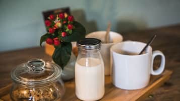 A wooden tray with a glass jar, a milk bottle, a white mug, and a small potted plant with red berries.