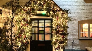 Een gebouw met een kerstboom versierd met lichtjes en versieringen, een bord waarop 
