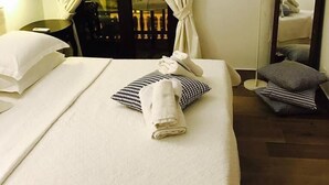 A hotel room with a bed, a chair, a table, a lamp, and a mirror.