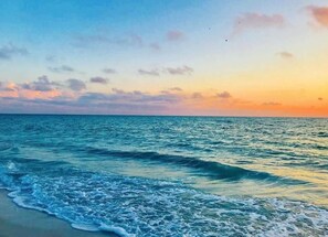 Platja amb onades i un cel al capvespre.