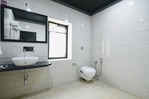 A bathroom with a white sink, a mirror, a toilet, and a shower.