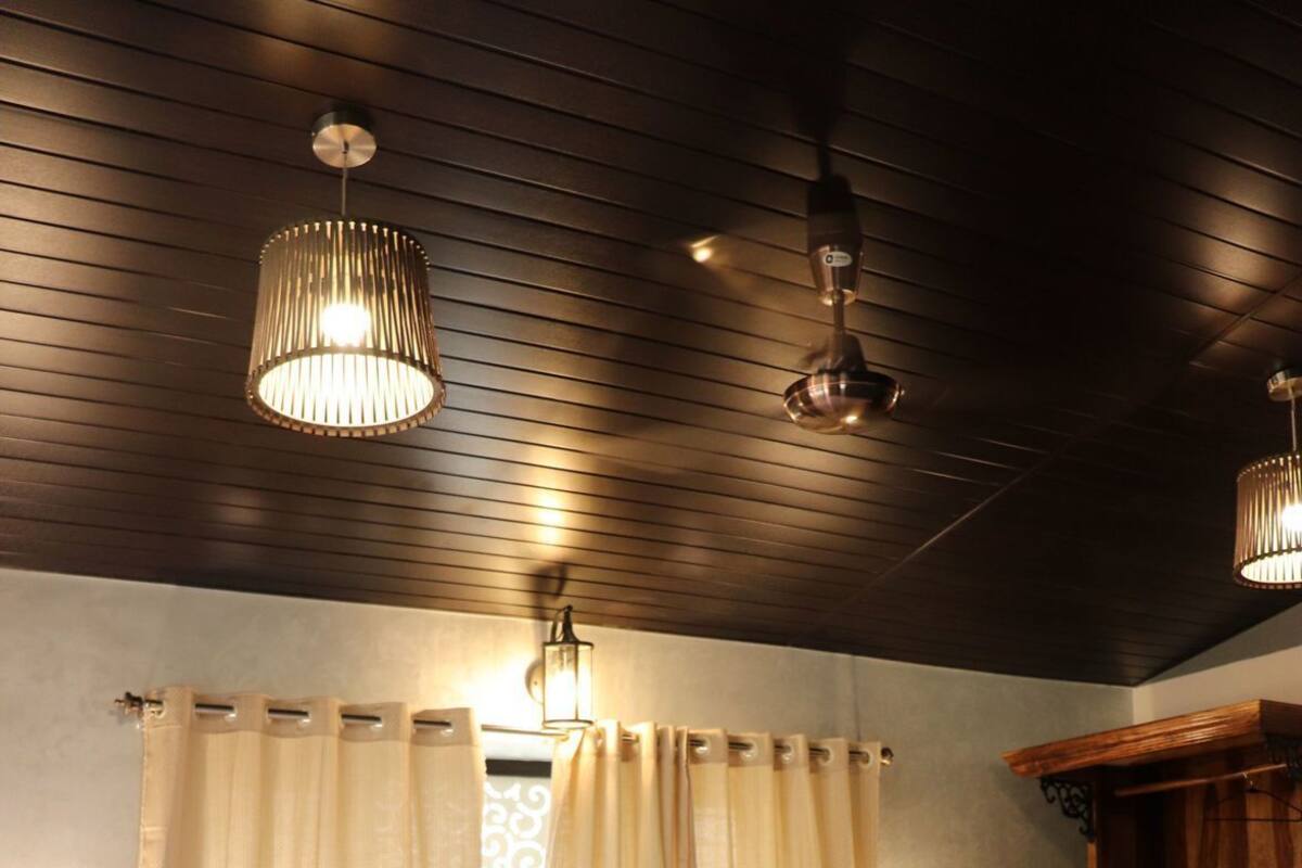 A bedroom with a bed, curtains, a wooden headboard, and pendant lights.