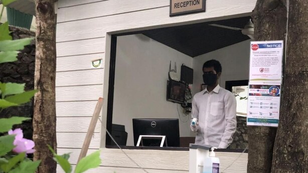 Zona d'entrada amb un rètol que diu 'RECEPTION', un monitor d'ordinador i un tauler d'anuncis amb informació sobre seguretat i salut.