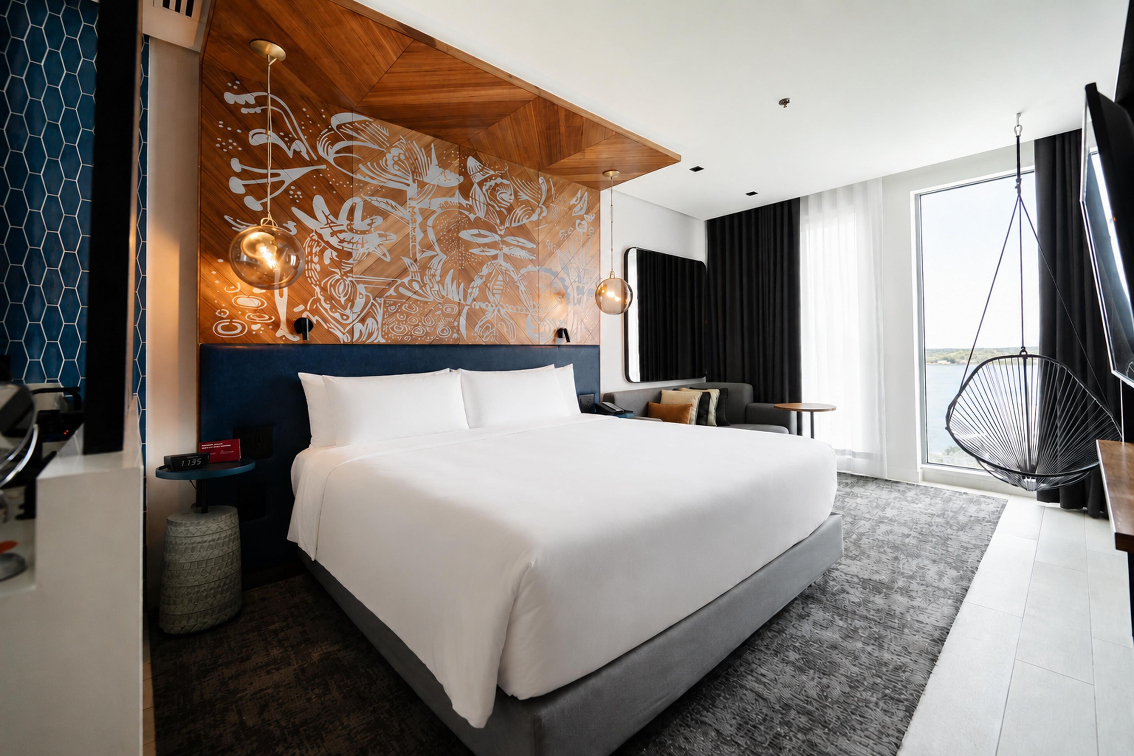 Ein modernes Hotelzimmer mit einem großen Bett, einem Schreibtisch und Blick ins Freie.