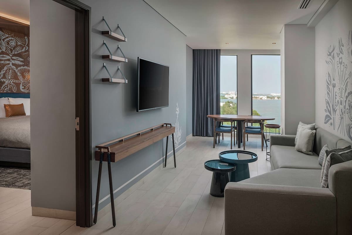 Una sala de estar moderna con un televisor de pantalla plana, un banco de madera, una mesa de comedor con sillas y un sofá.