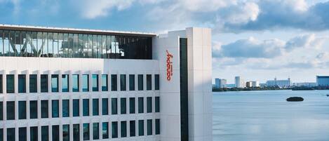 A modern building with a glass facade and a clear view of the water and city skyline in the background.