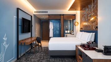 A modern hotel room with a bed, desk, chair, and a TV.