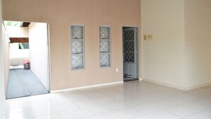 A hallway with a beige wall, three windows with diamond-patterned glass, and a door with a metal grille. - HOUSE WITH HEATED POOL Solar, air conditioning, Wi-Fi, and TV with Netflix! Sleeps 13 people (Olímpia)