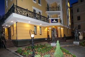 A hotel with a yellow facade, black iron balcony railing, and a statue in front. - Mandarin ClubHouse (Kharkiv)