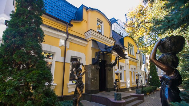A yellow building with a blue roof, surrounded by trees and featuring statues. - Mandarin ClubHouse (Kharkiv)