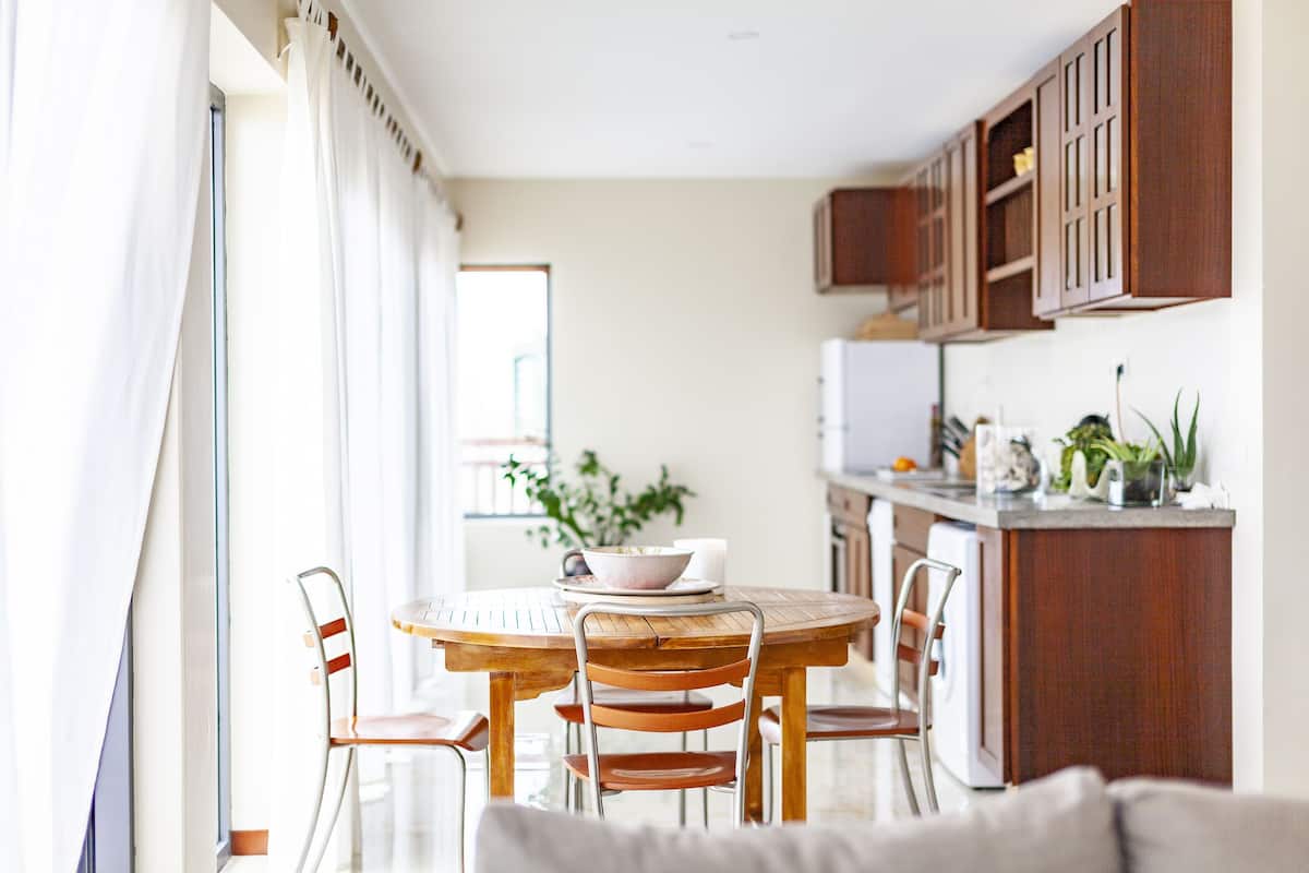 Une cuisine moderne avec des meubles en bois, une table à manger avec des chaises et un îlot de cuisine agrémenté de plantes.