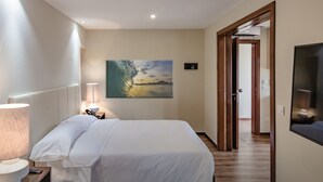 Une chambre d’hôtel avec un lit, un tableau, une lampe et un plancher en bois.