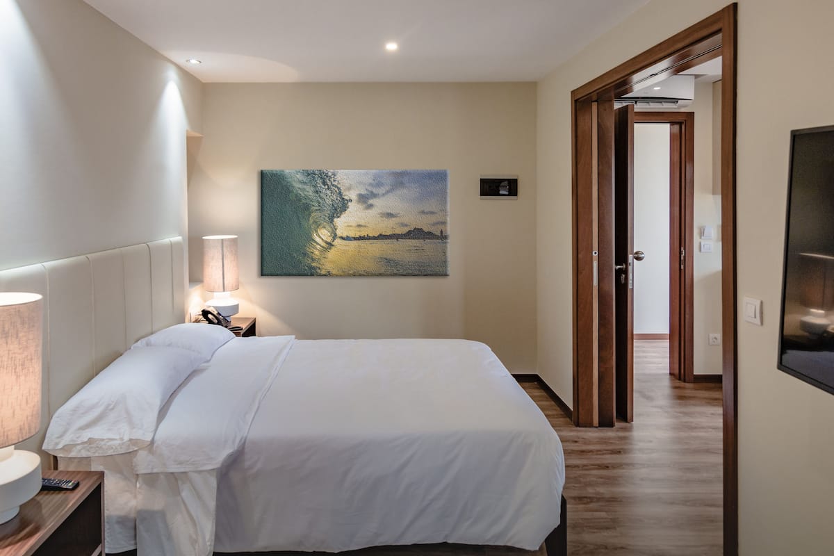 Une chambre d’hôtel avec un lit, un tableau, une lampe et un plancher en bois.
