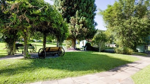 Un parque con un sendero de piedra, bancos y un carrito de madera.